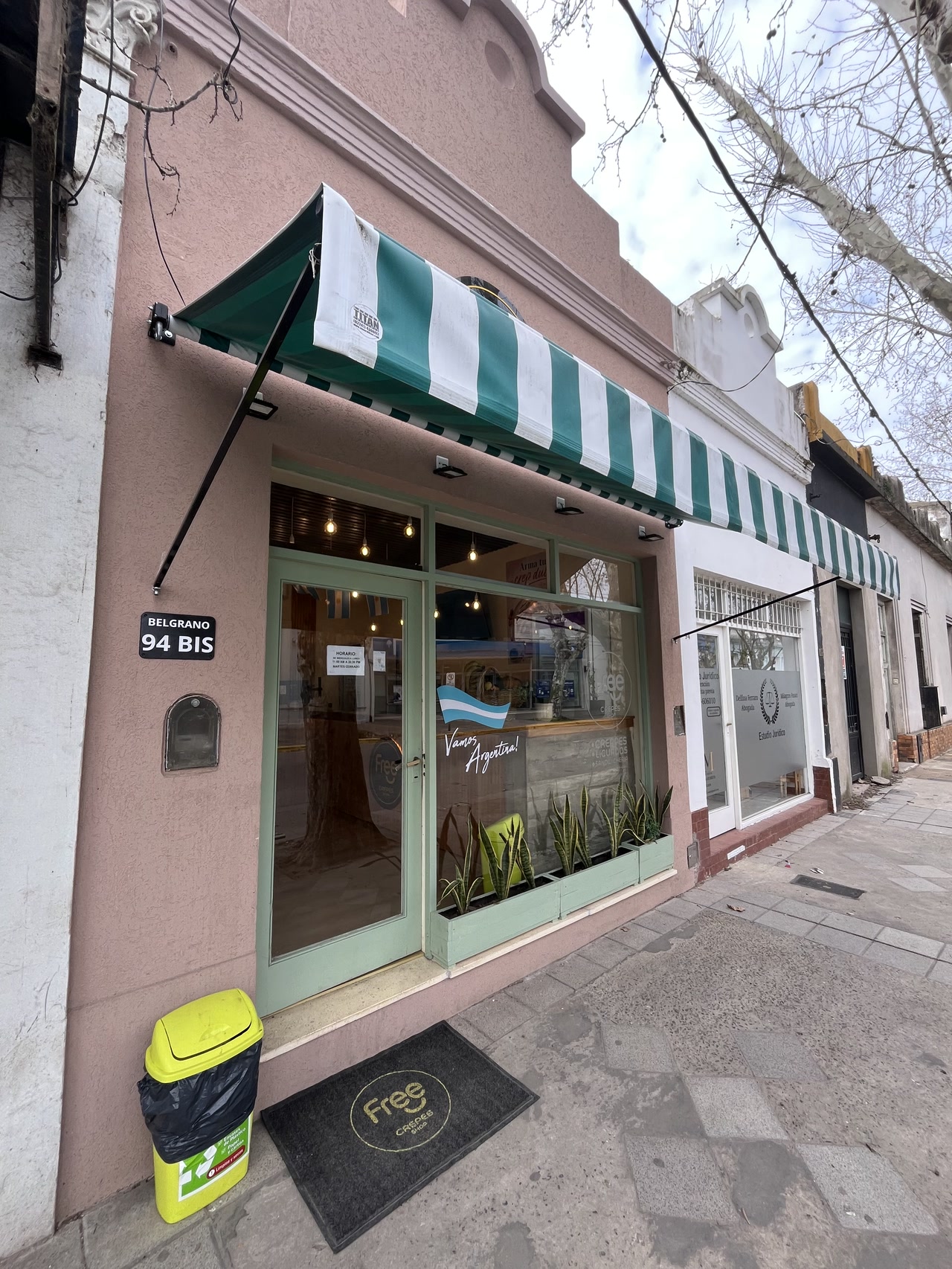 Fachada completa de Free Crepes en Belgrano 94, con toldo verde y cartel en la vereda